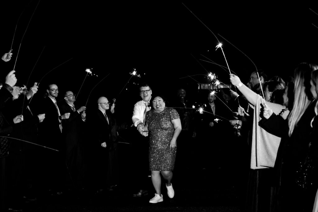 bride and groom walking under lit sparklers