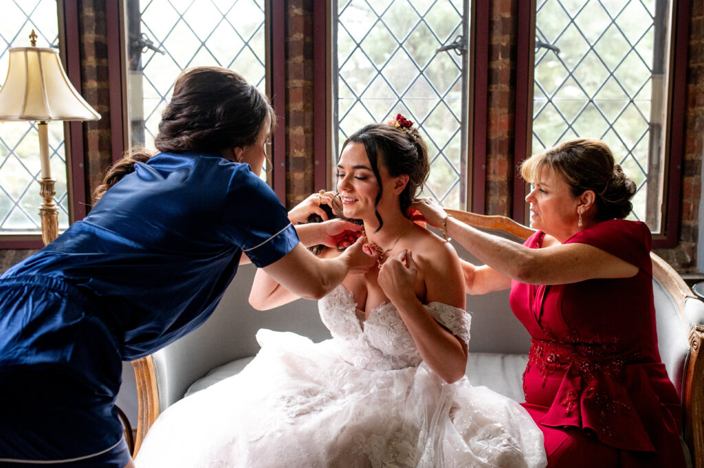bridesmaid and mom helping bride with her jewelry