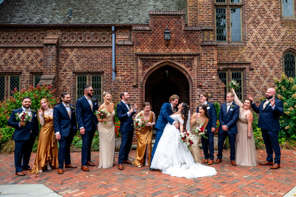 bridal party looking at bride and groom as they kiss