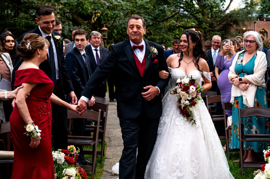 bride walking down the aisle with her dad as he grabs woman's hand
