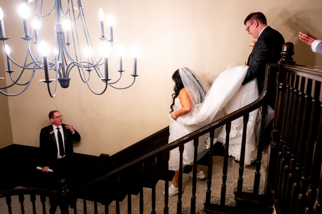 bride walking down steps while groom holds dress