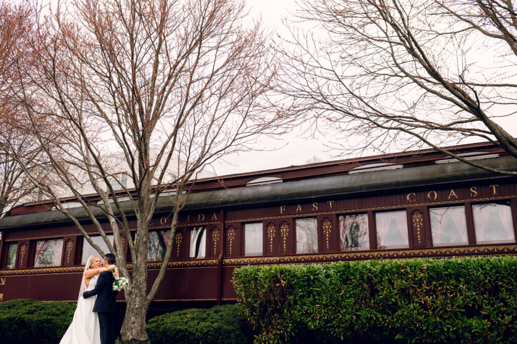 bride and groom hugging in front of a traincar