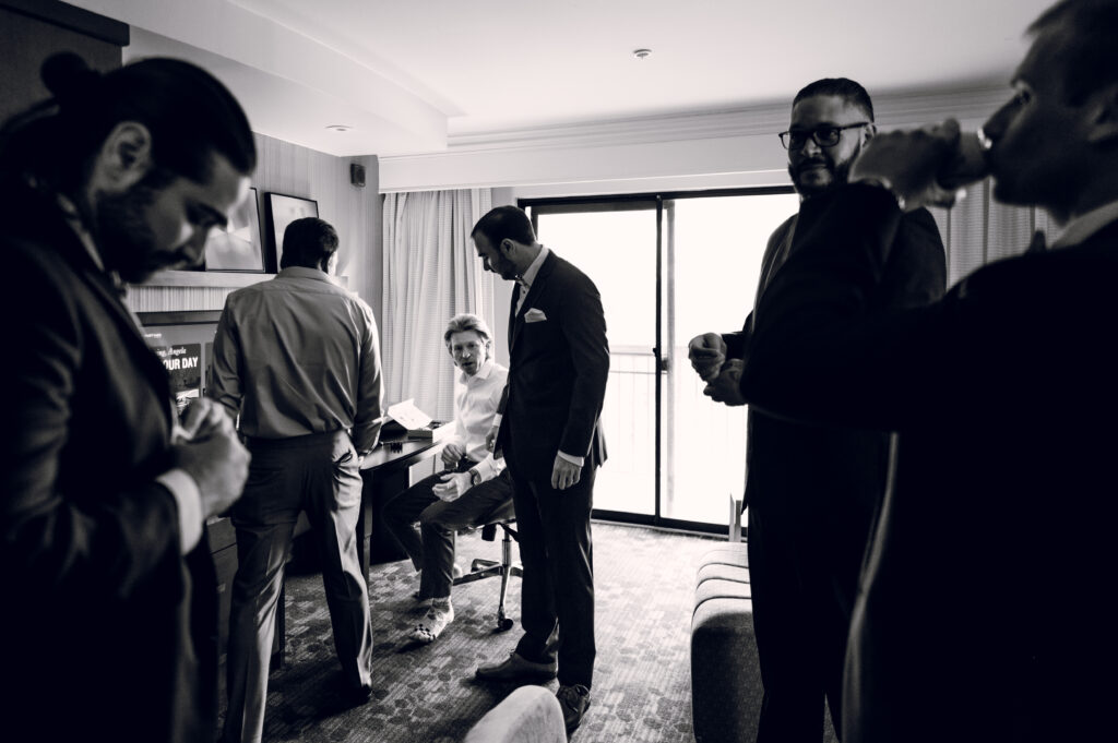 groomsmen looking at groom in hotel room