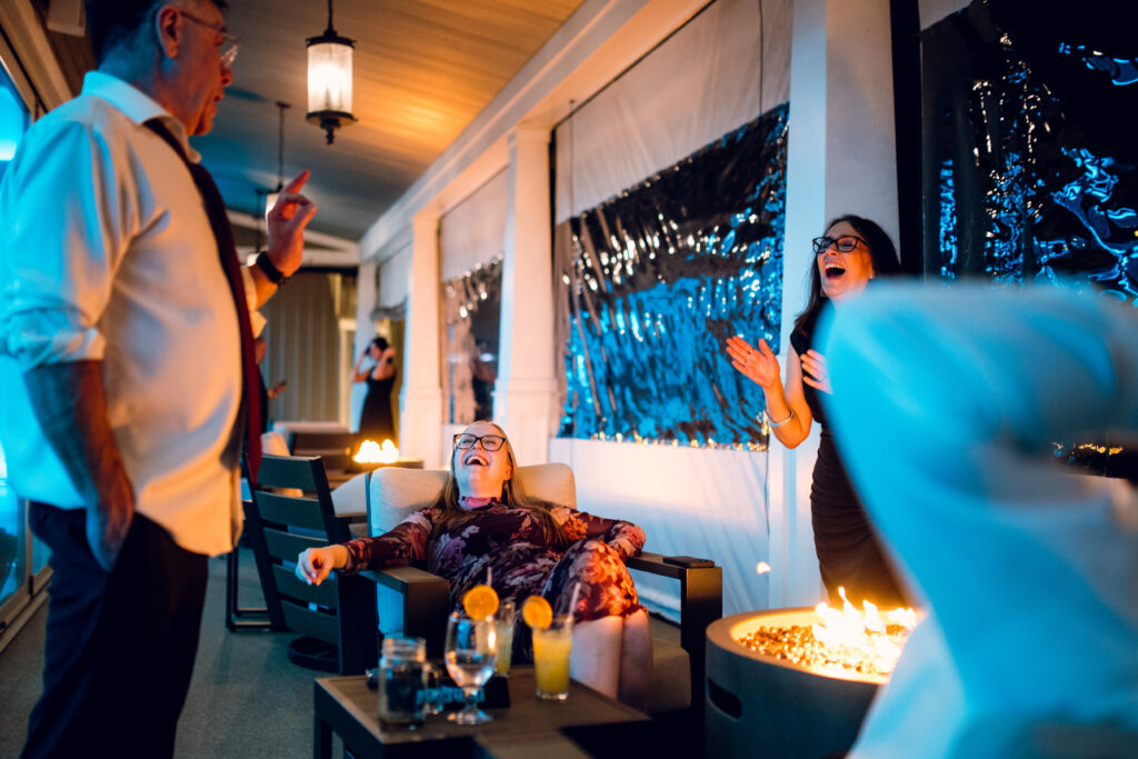 people sitting and laughing around a fire pit