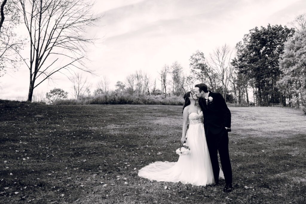 bride and groom kissing in a field