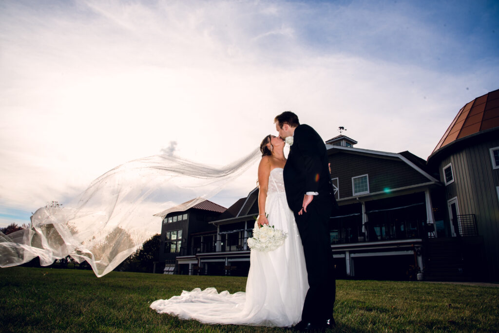 bride and groom kissing with a veil flying in front of bear brook valley