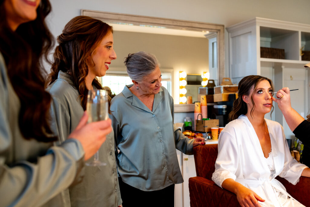bride getting makeup while girls look on